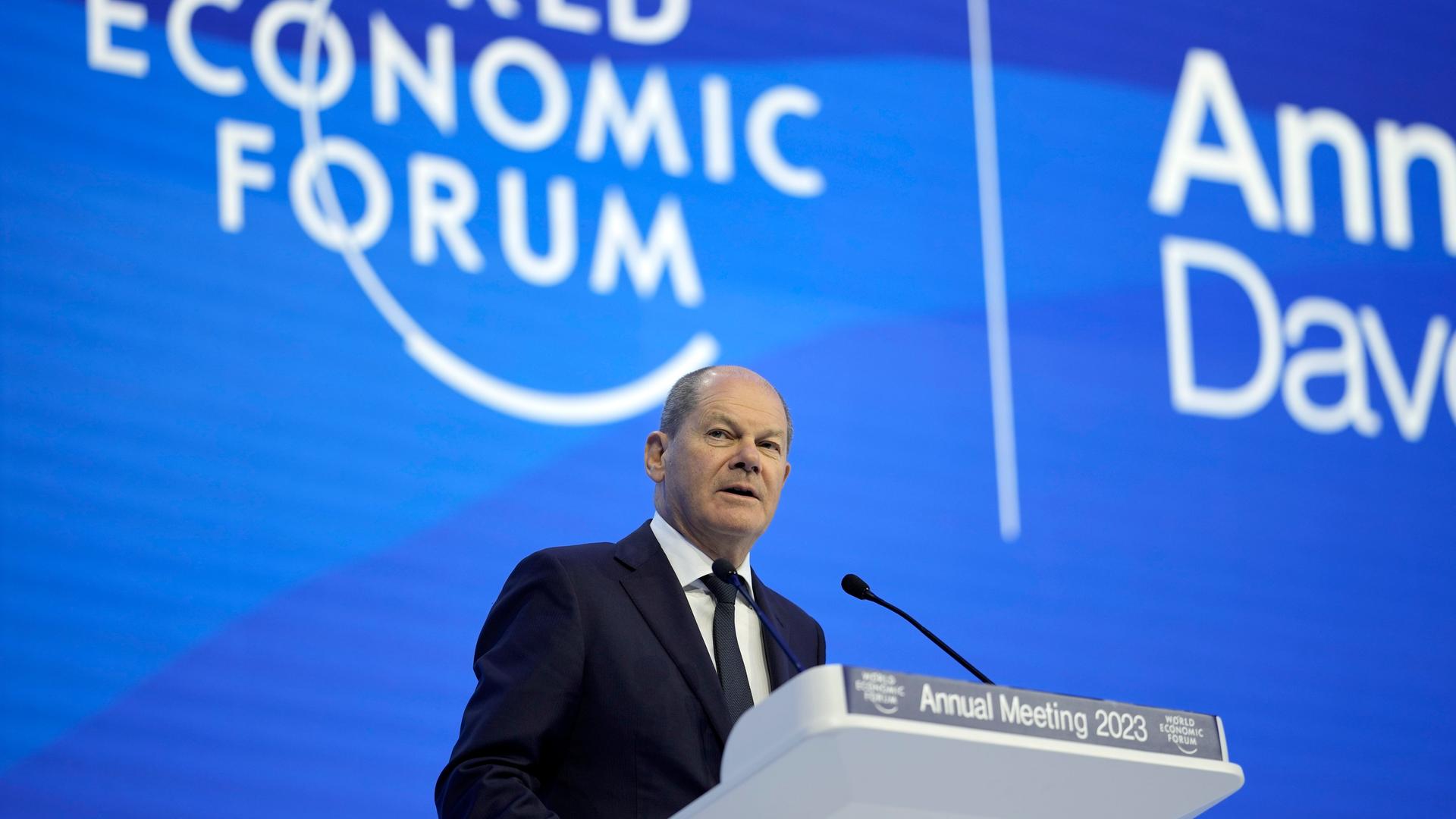 Bundeskanzler Olaf Scholz spricht auf dem Welt-Wirtschafts-Forum in Davos. Er steht vor einer blauen Wand an einem Redner-Pult Bundeskanzler Olaf Scholz spricht auf dem Welt-Wirtschafts-Forum in Davos. Er steht vor einer blauen Wand an einem Redner-Pult