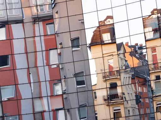 Unterschiedliche Wohnhäuser in der Kölner Innenstadt spiegeln sich in einer gegenüberliegenden Glasfassade