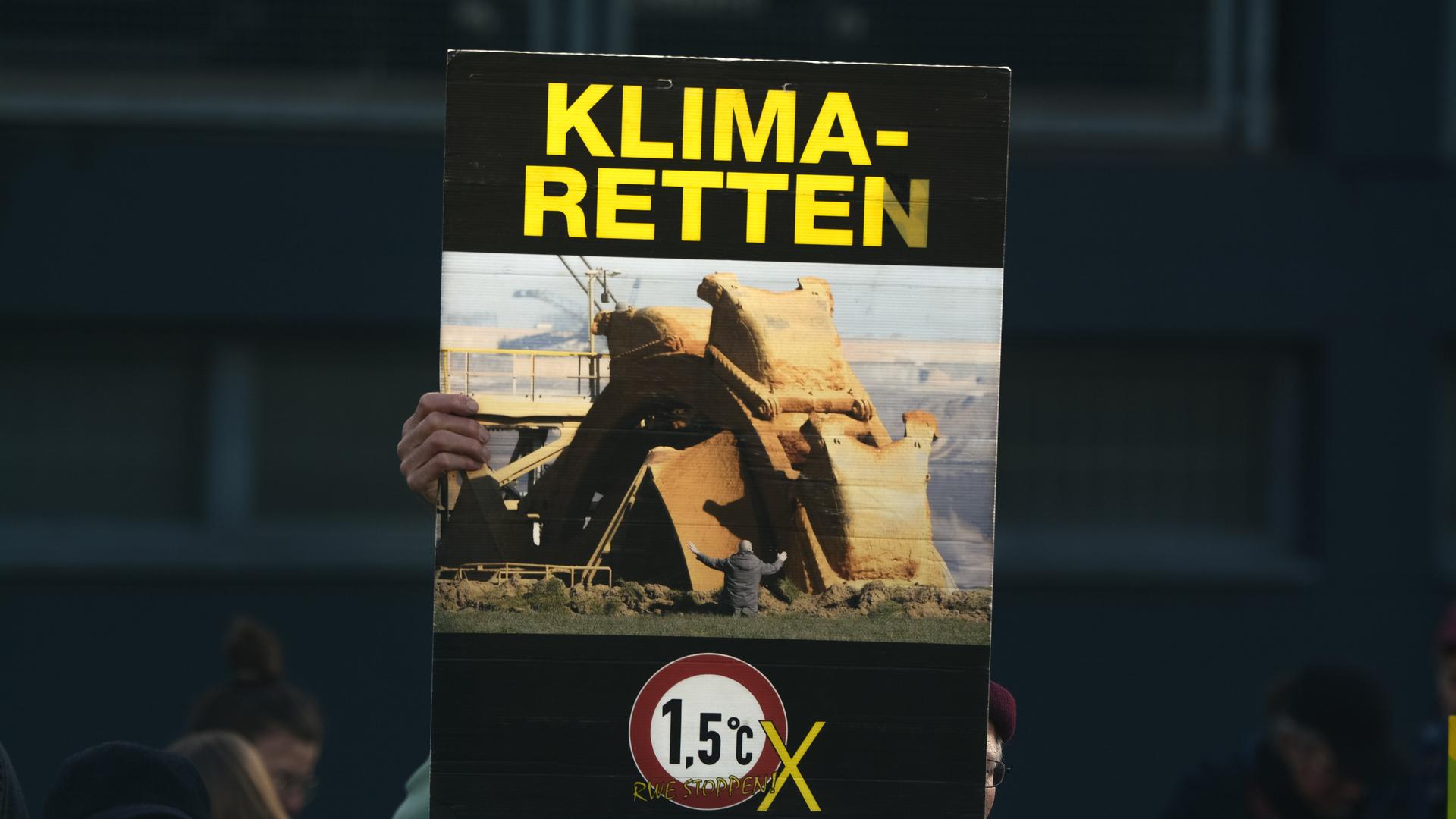 Eine Frau hält ein Plakat in die Höhe auf dem "KLIMA-RETTEN" geschrieben steht Eine Frau hält ein Plakat in die Höhe auf dem "KLIMA-RETTEN" geschrieben steht