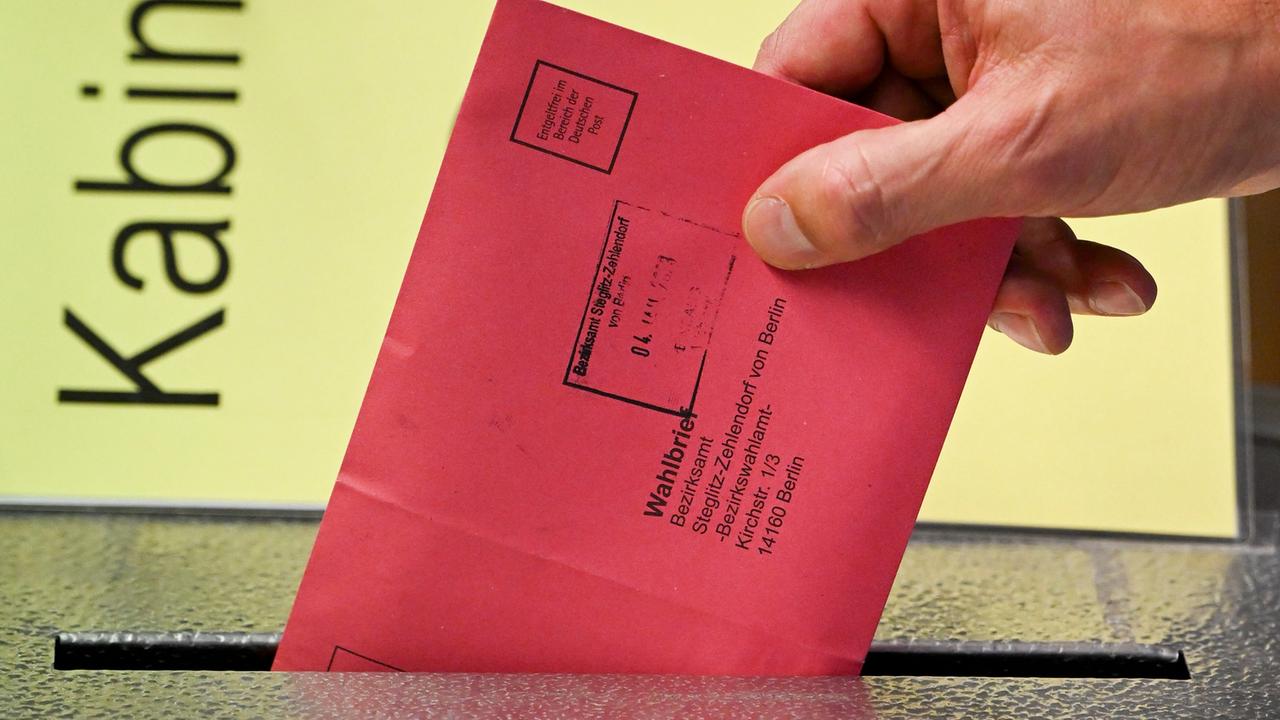Zum Beginn der Briefwahl für die Wiederholungswahlen am 12. Februar zum Abgeordnetenhaus in Berlin wählt ein Mann  vorab  und steckt seine Stimmzettel in einem roten Briefumschlag für die Briefwahl in die Wahlurne.Zu sehen ist nur seine Hand.