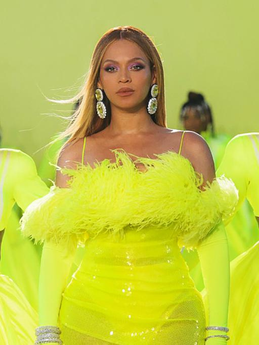 Die Sängerin Beyoncé mit ihren Tänzerinnen in neongelben Kostümen beim Bühnenauftritt.