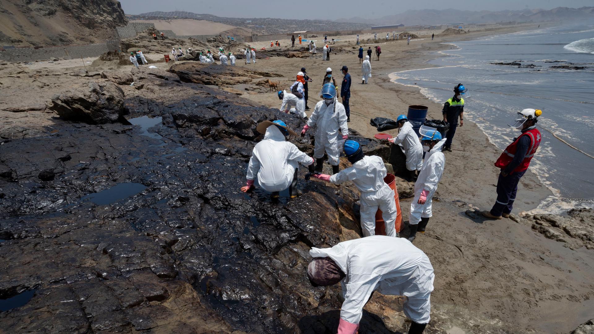 Menschen versuchen, einen Strand in Peru vom Öl zu reinigen.