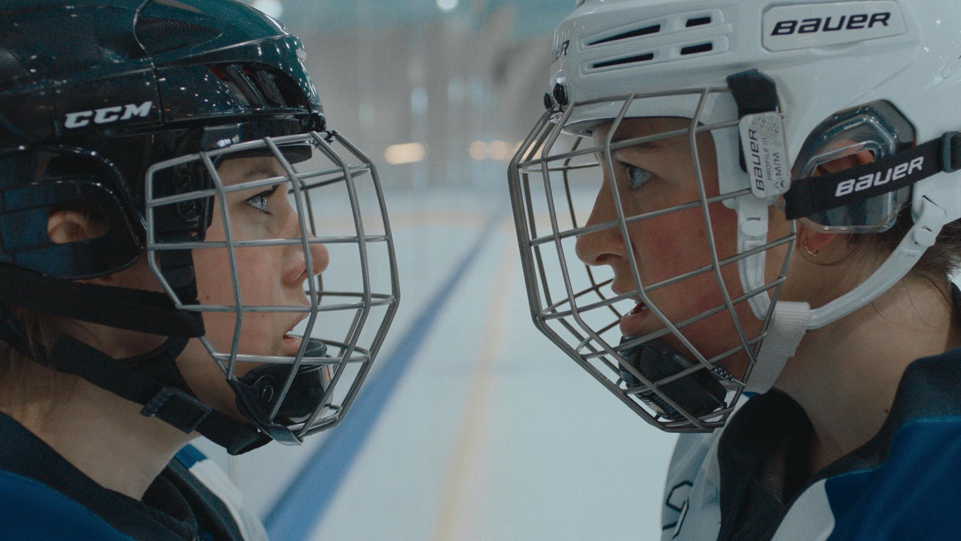 Zwei Eishockeyspielerinnen stehen sich gegenüber und fixieren einander mit Blicken.