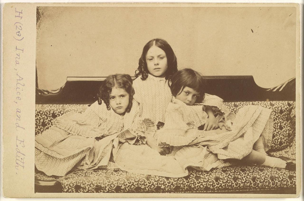 Historische Aufnahme (in Sepia-Tönung) der Geschwister Edith, Ina und Alice Liddell auf einem Sofa im Sommer 1858. Historische Aufnahme (in Sepia-Tönung) der Geschwister Edith, Ina und Alice Liddell auf einem Sofa im Sommer 1858.
