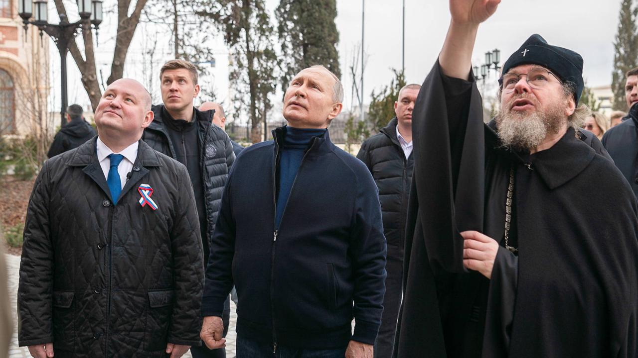 Der russische Präsident wird bei seinem Besuch auf der annektierten Halbinsel Krim von mehreren Männern begleitet. Der russische Präsident wird bei seinem Besuch auf der annektierten Halbinsel Krim von mehreren Männern begleitet.