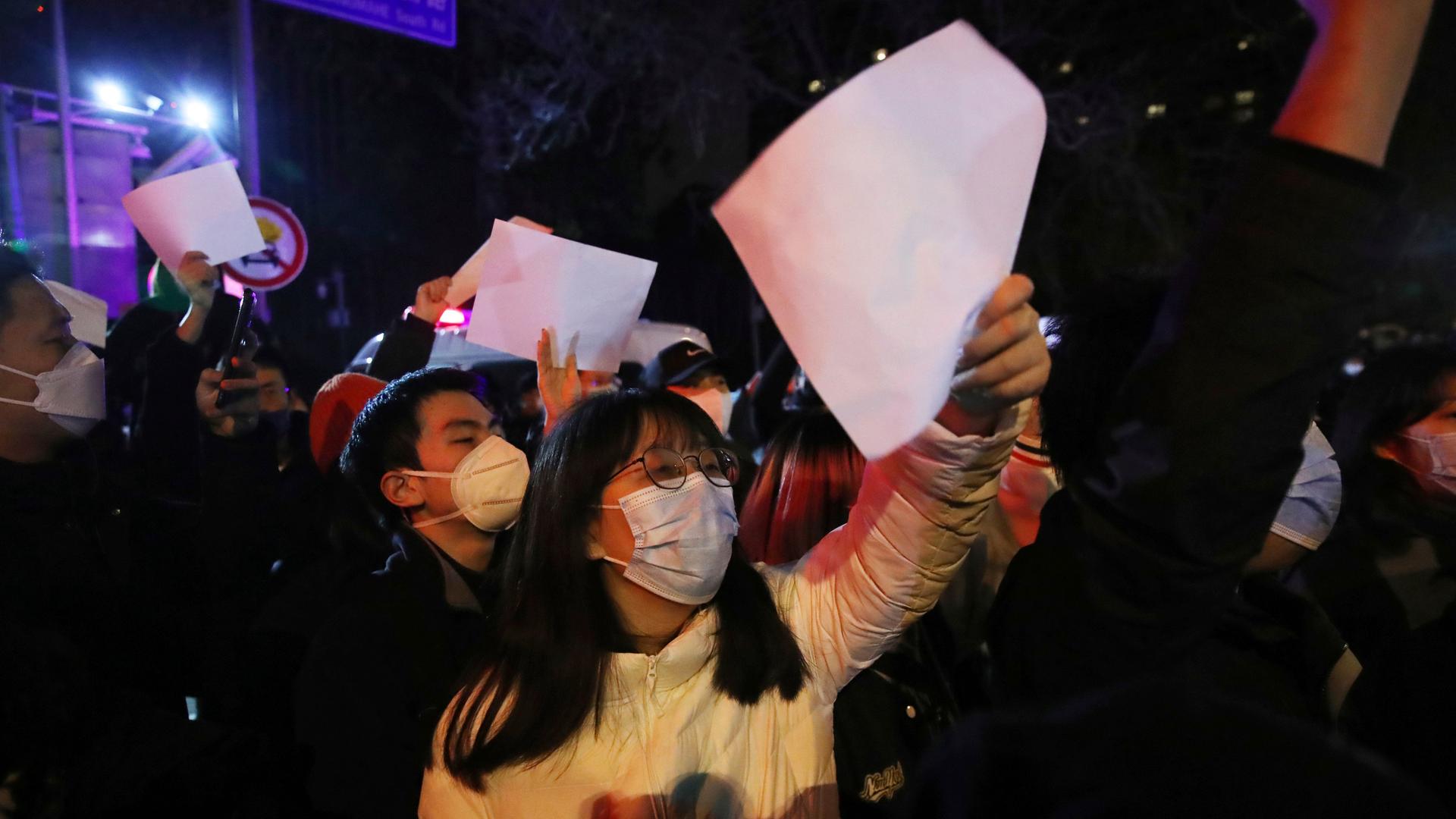 Mehrere Menschen demonstrieren gegen die Null-Covid-Politik in China und halten weiße, unbeschriftete Zettel in die Höhe. Mehrere Menschen demonstrieren gegen die Null-Covid-Politik in China und halten weiße, unbeschriftete Zettel in die Höhe.