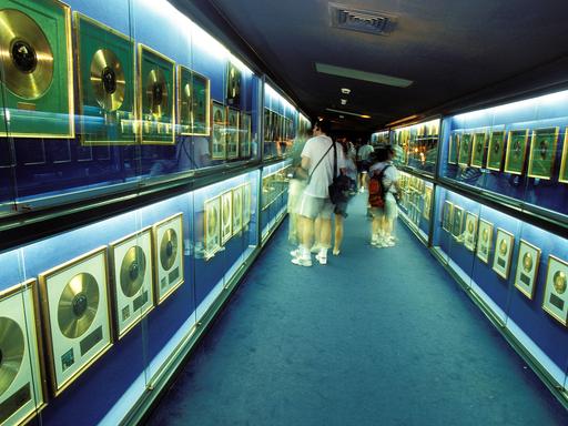 Besucher stehen in einem Raum mit zahlreichen Goldenen Schallplatten in gläsernen Vitrinen.