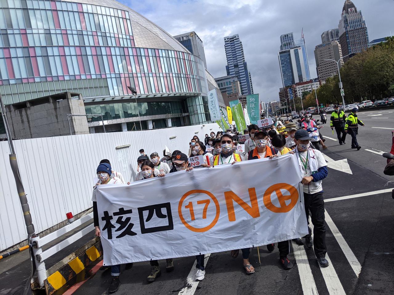 Eine Demonstration mit wenigen Dutzend Teilnehmern zieht durch eine breite Straße in Taiwan. In der ersten Reihe Demonstrierende mit einem großen weißen Transparent.