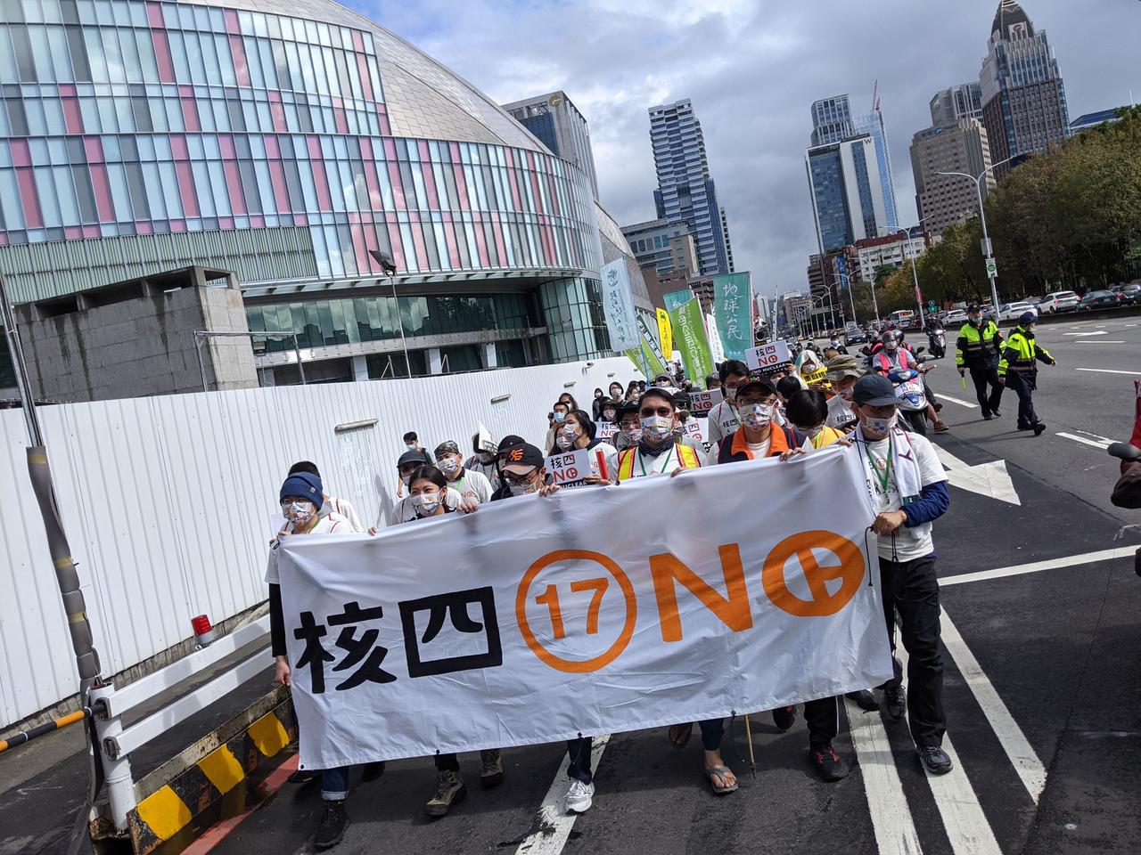 Eine Demonstration mit wenigen Dutzend Teilnehmern zieht durch eine breite Straße in Taiwan. In der ersten Reihe Demonstrierende mit einem großen weißen Transparent. Eine Demonstration mit wenigen Dutzend Teilnehmern zieht durch eine breite Straße in Taiwan. In der ersten Reihe Demonstrierende mit einem großen weißen Transparent.