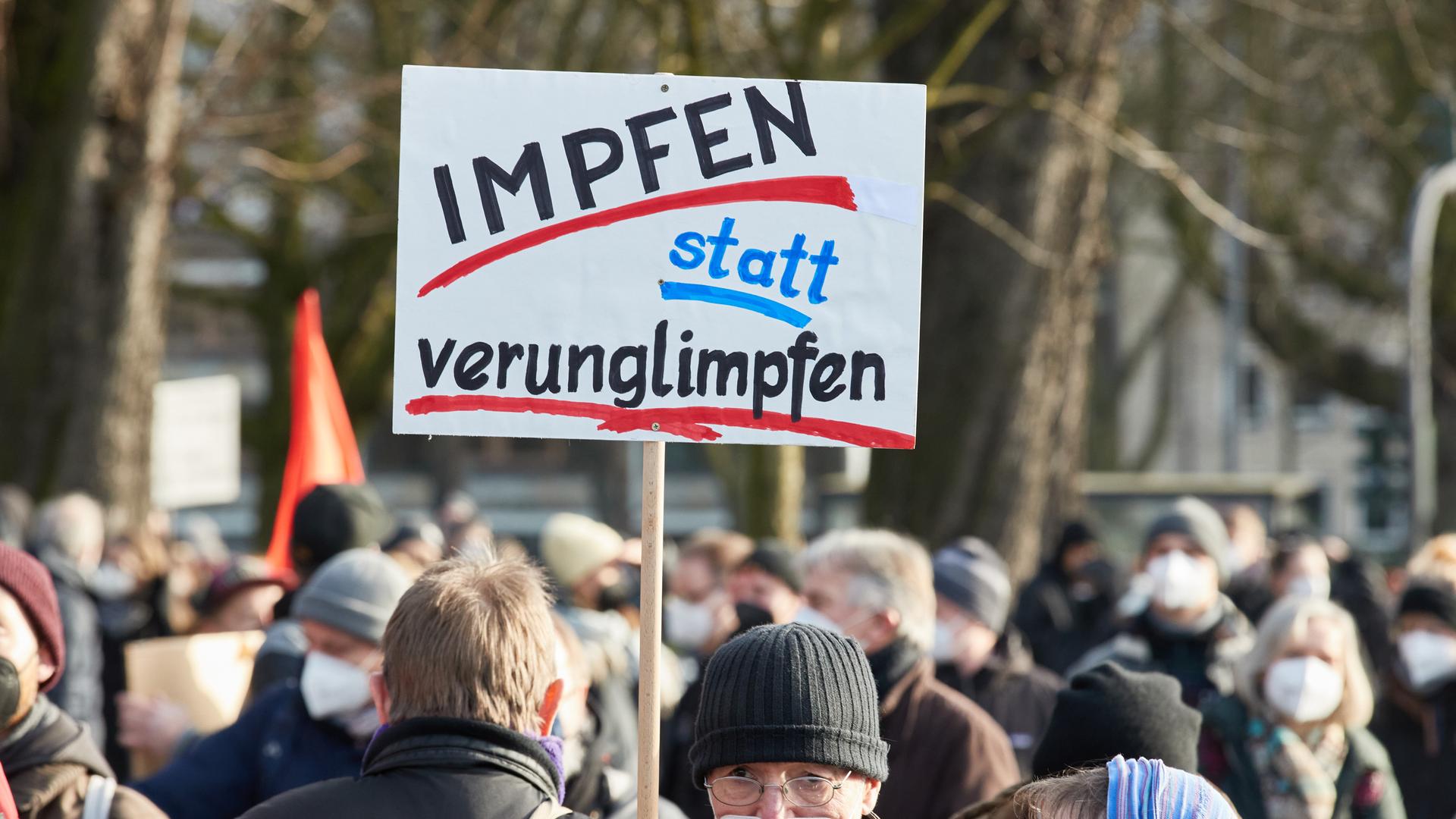 Ein Teilnehmer einer Demonstration hält ein Transparent mit der Aufschrift "Impfen statt verunglimpfen!" auf der Mohrweide am Dammtorbahnhof in Hamburg. 