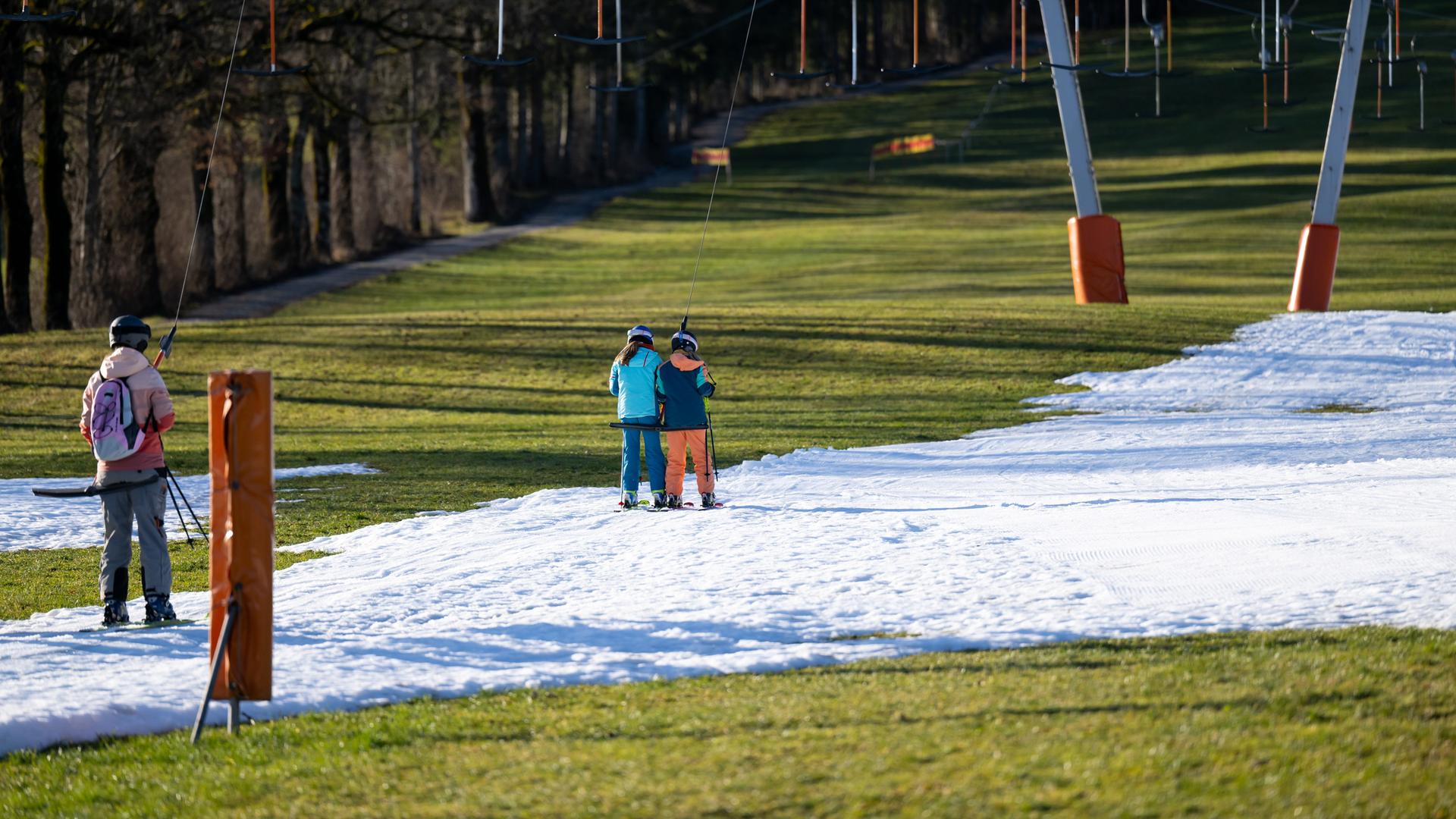 Wintersportler fahren am Draxlhang im Skigebiet Brauneck mit einem Schlepplift die Piste hinauf. Wintersportler fahren am Draxlhang im Skigebiet Brauneck mit einem Schlepplift die Piste hinauf.