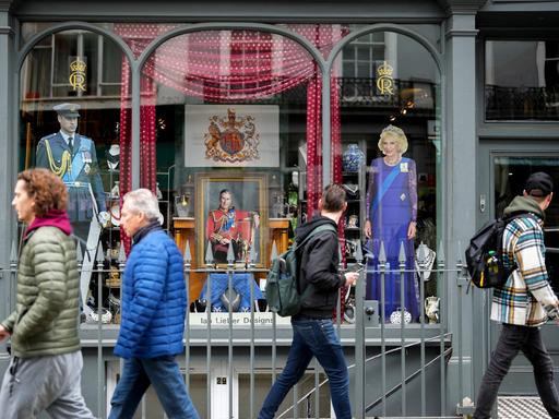 Menschen laufen an einem Schaufenster mit der Darstellung von König Charles III. in London vorbei.