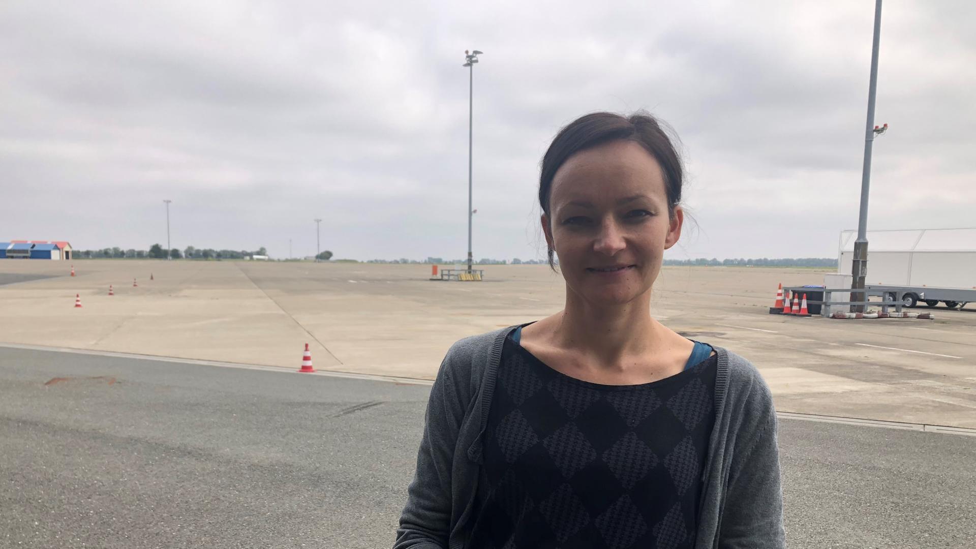 Eine junge Frau steht auf dem Rollfeld eines Flughafens