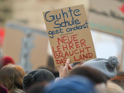 Bei einer Demonstration wird ein Schild mit der Aufschrift "Guhte Schule geet anderst. Neue Lehrer braucht das Land" hochgehalten