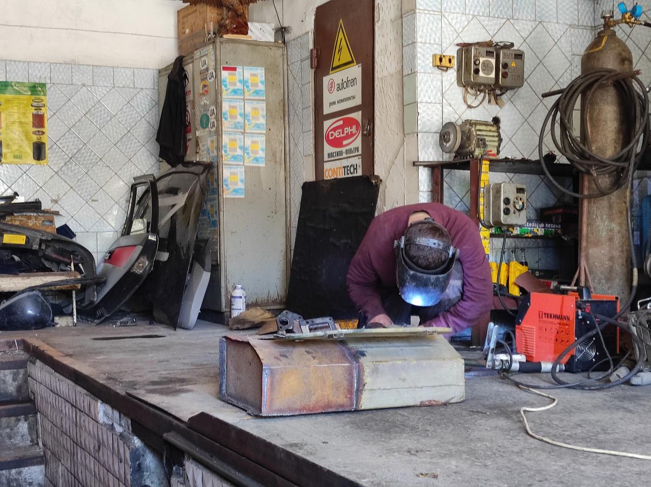 Eine Person schweißt in einer Garage. Eine Person schweißt in einer Garage.