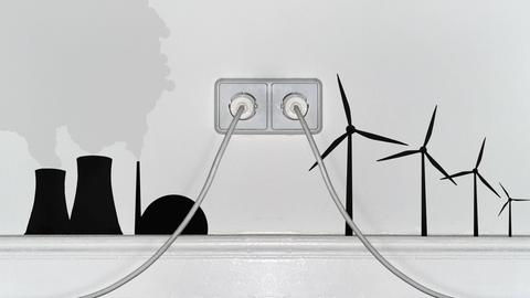 Zwei Steckdosen in einer Wohnungswand. Atomenergie und Windkraft Zeichnungen rechts und links davon.