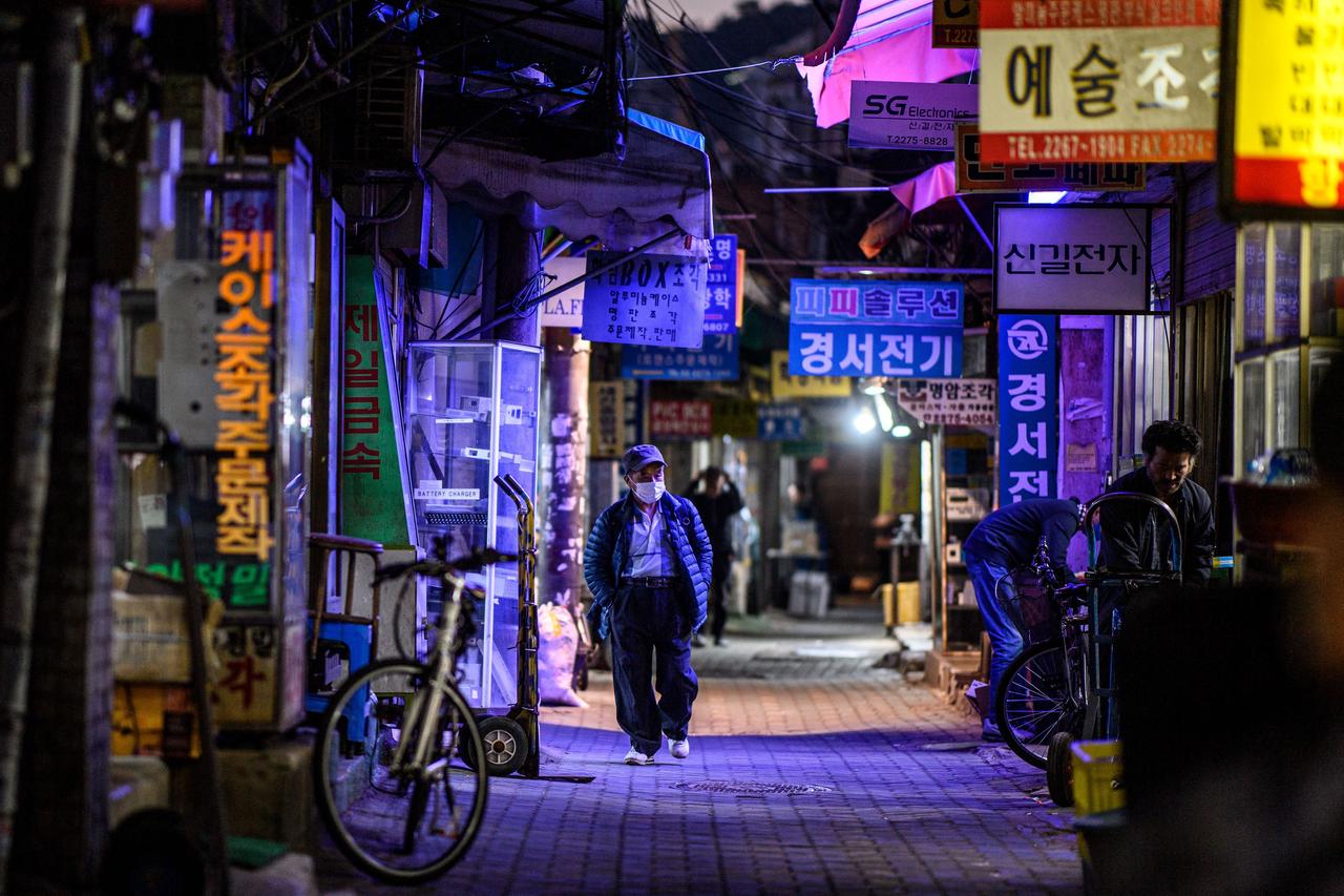 Ein älterer Mann läuft durch eine erleuchtete Straße in Seoul. Ein älterer Mann läuft durch eine erleuchtete Straße in Seoul.