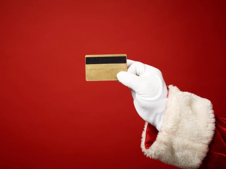 Illustration: Die Hand des Weihnachtsmanns hält eine goldene Kreditkarte.