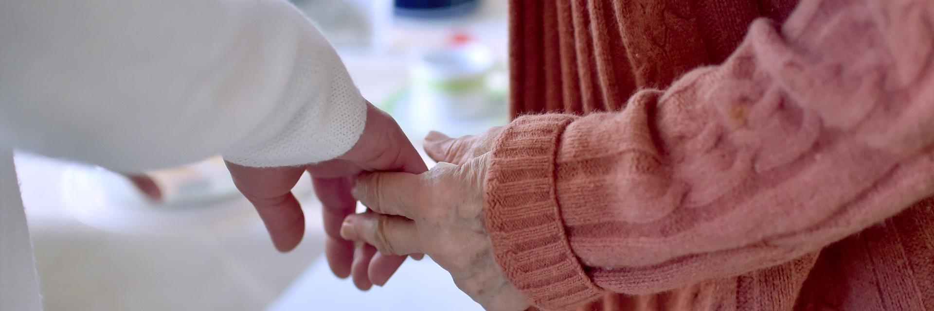Eine Pflegekraft hält die Hand einer Bewohnerin einer Pflegeeinrichtung Eine Pflegekraft hält die Hand einer Bewohnerin einer Pflegeeinrichtung