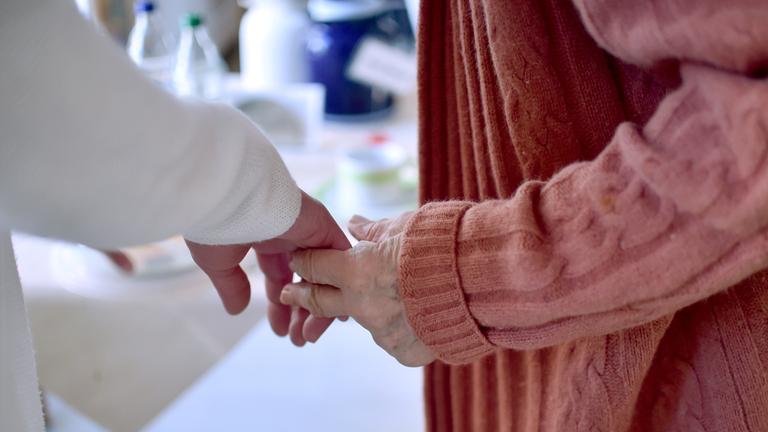 Eine Pflegekraft hält die Hand einer Bewohnerin einer Pflegeeinrichtung Eine Pflegekraft hält die Hand einer Bewohnerin einer Pflegeeinrichtung