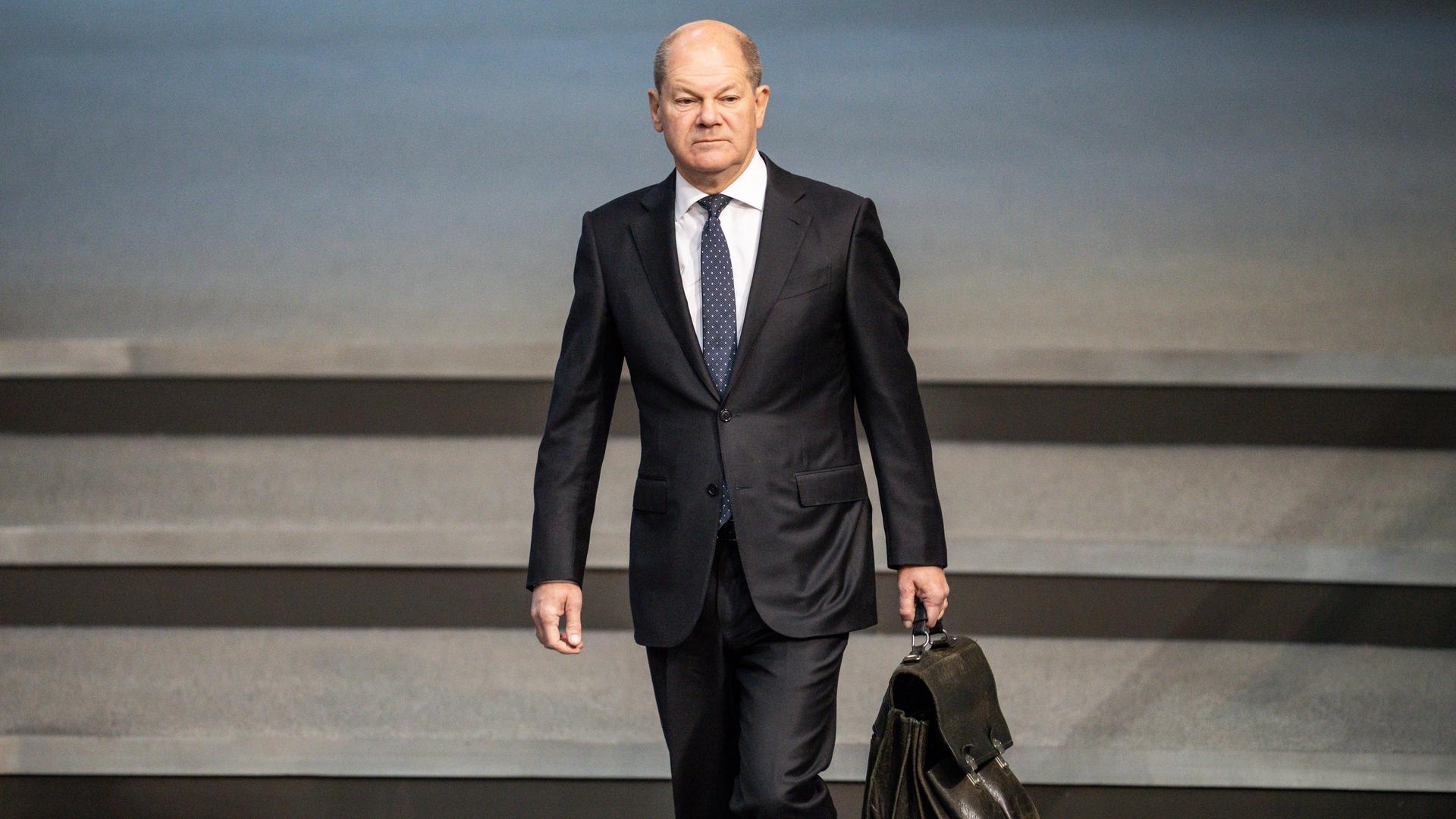 Bundeskanzler Olaf Scholz (SPD). Ein Mann läuft mit einer Aktentasche eine Treppe entlang.