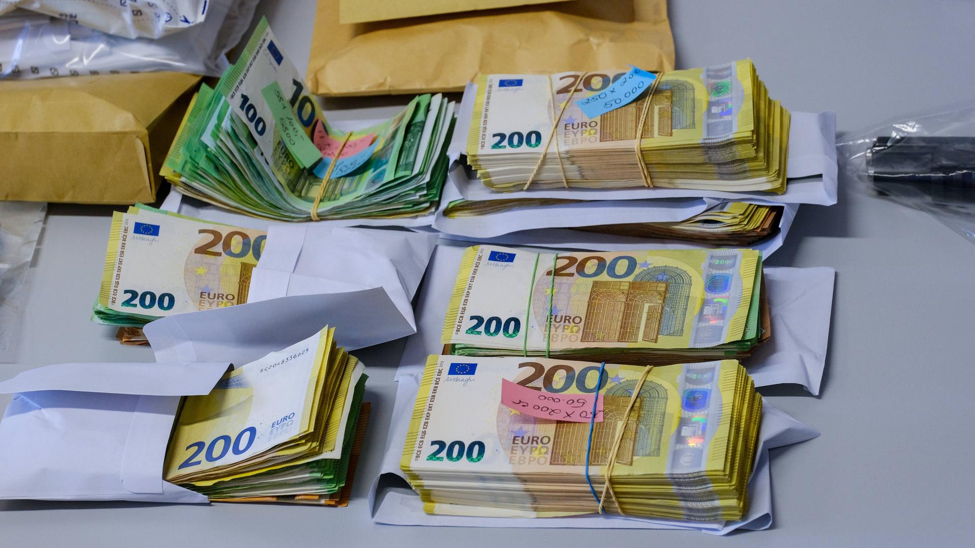 Auf einem Tisch liegen mehrere Bündel mit Geldscheinen, die bei einer Razzia im Zusammenhang mit Geldwäsche gefunden wurden Auf einem Tisch liegen mehrere Bündel mit Geldscheinen, die bei einer Razzia im Zusammenhang mit Geldwäsche gefunden wurden