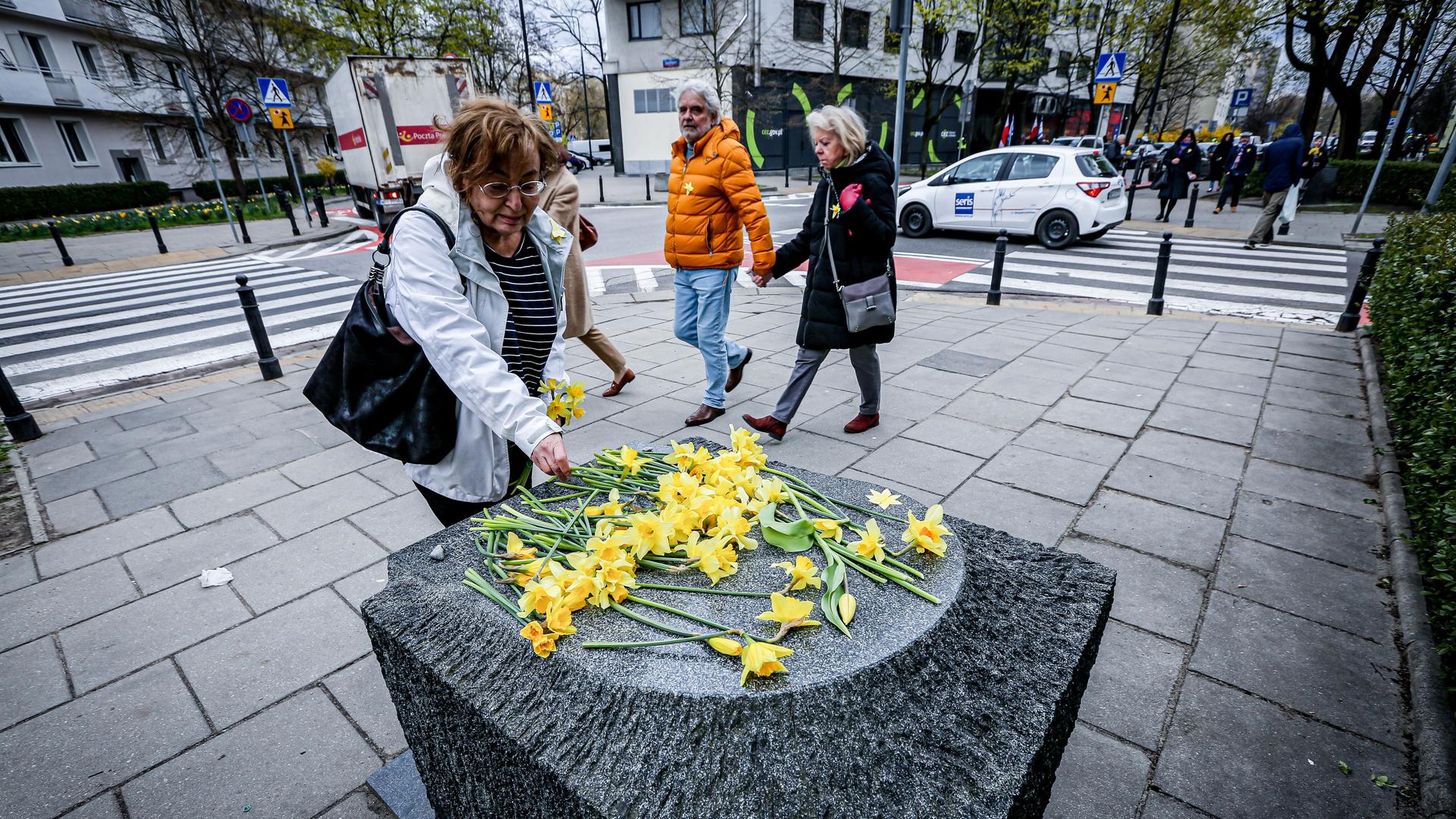 Eine Frau legt gelbe Blumen am Denkmal für die Ghetto-Helden im Warschauer Stadtteil Muranow ab