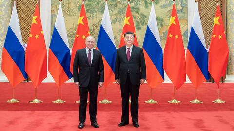 Der chinesische President Xi Jinping und der russische President Vladimir Putin stehen nebeneinander. Im Hintergrund russische und chinesische Flaggen.