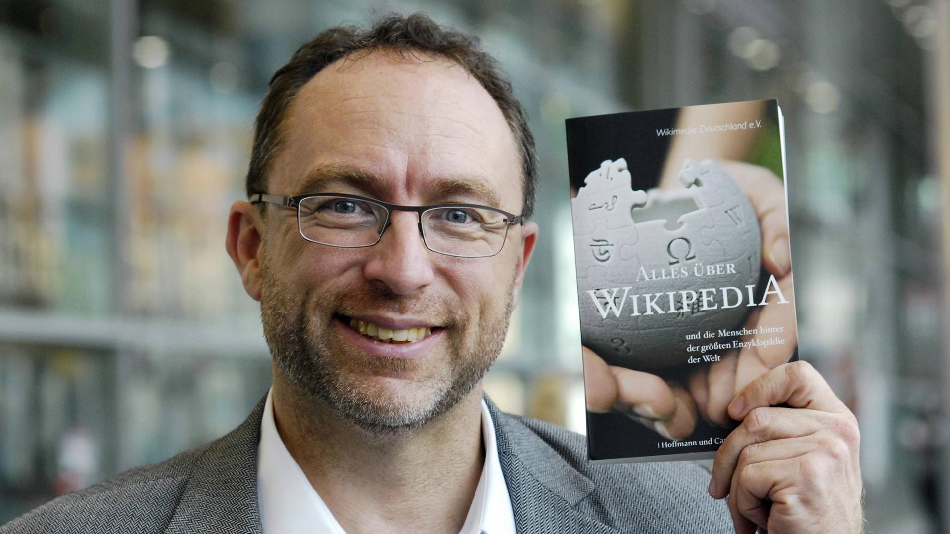 Jimmy Wales hält Buch „Alles über Wikipedia“ hoch. Jimmy Wales hält Buch „Alles über Wikipedia“ hoch.