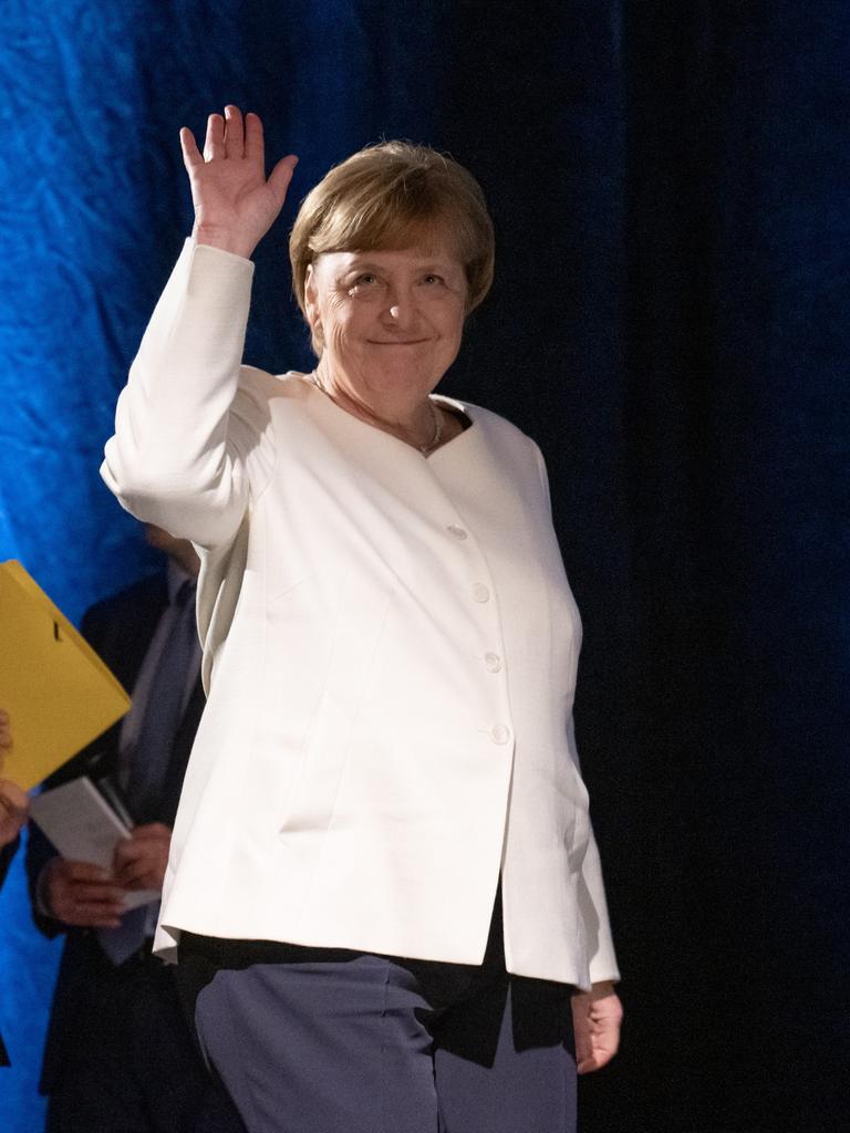 Angela Merkel. Eine Frau geht auf eine Bühne und winkt.