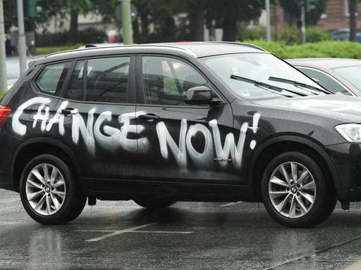 Ein mit den Worten "Change Now!" beschmierter SUV der Marke BMW fährt durch die Frankfurter Innenstadt.
