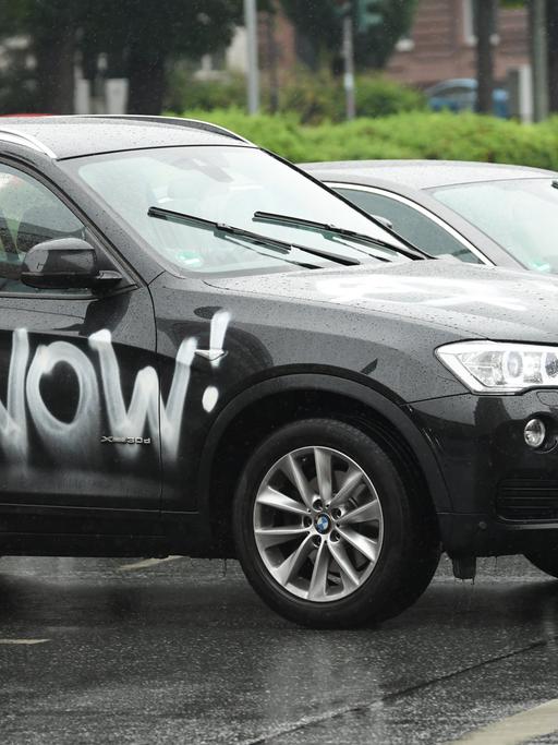 Ein mit den Worten "Change Now!" beschmierter SUV der Marke BMW fährt durch die Frankfurter Innenstadt.