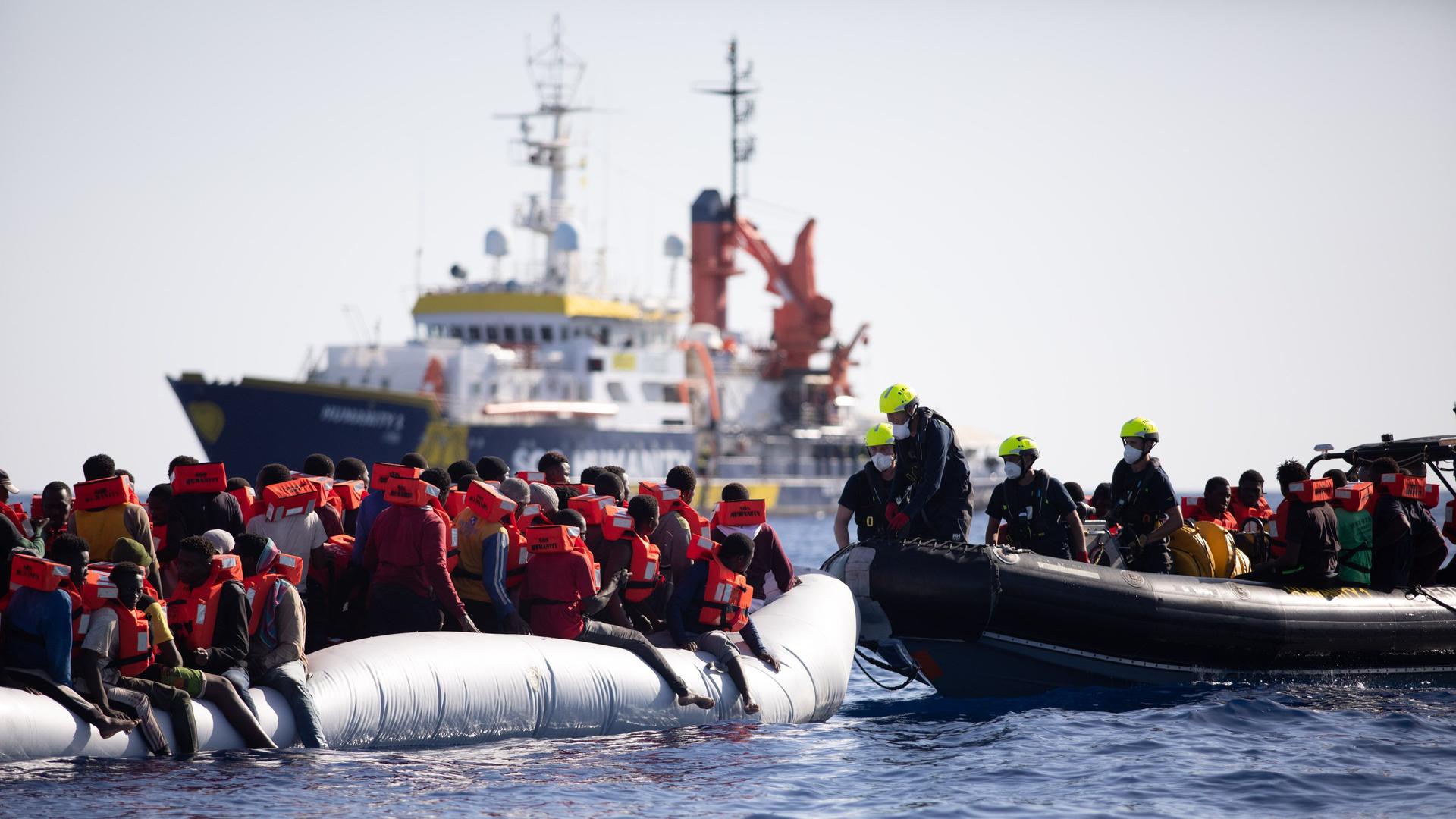 Das Foto zeigt das deutsche Seenotrettungsboot "Humanity 1". Im Vordergrund ist ein Schlauboot mit Bootsflüchtlingen zu sehen. Das Foto zeigt das deutsche Seenotrettungsboot "Humanity 1". Im Vordergrund ist ein Schlauboot mit Bootsflüchtlingen zu sehen.