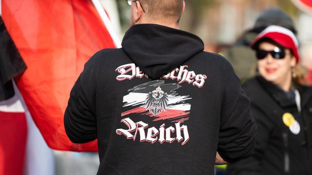 Ein Mann trägt einen Pullover mit dem Aufdruck "Deutsches Reich" bei einer Demonstration von Reichsbürgern. Sogenannte Reichsbürger und andere Demokratiegegner demonstrieren in der Nähe des Neuen Palais.