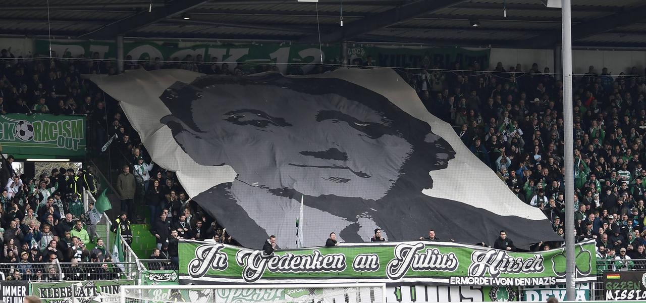 Bei einem Fußballspiel von Greuther Fürth haben Fans ein großes Transparent in Gedenken an den ehemaligen Spieler Julius Hirsch entrollt. Bei einem Fußballspiel von Greuther Fürth haben Fans ein großes Transparent in Gedenken an den ehemaligen Spieler Julius Hirsch entrollt.