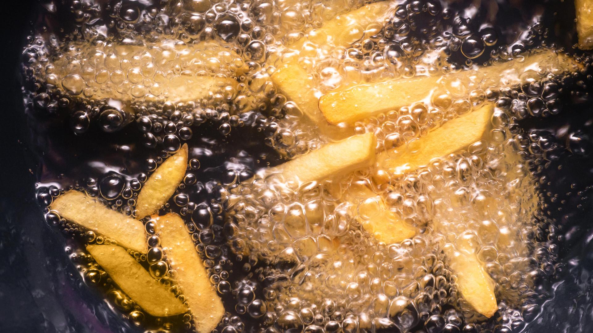 Pommes Frites werden in heißen Öl frittiert. Pommes Frites werden in heißen Öl frittiert.