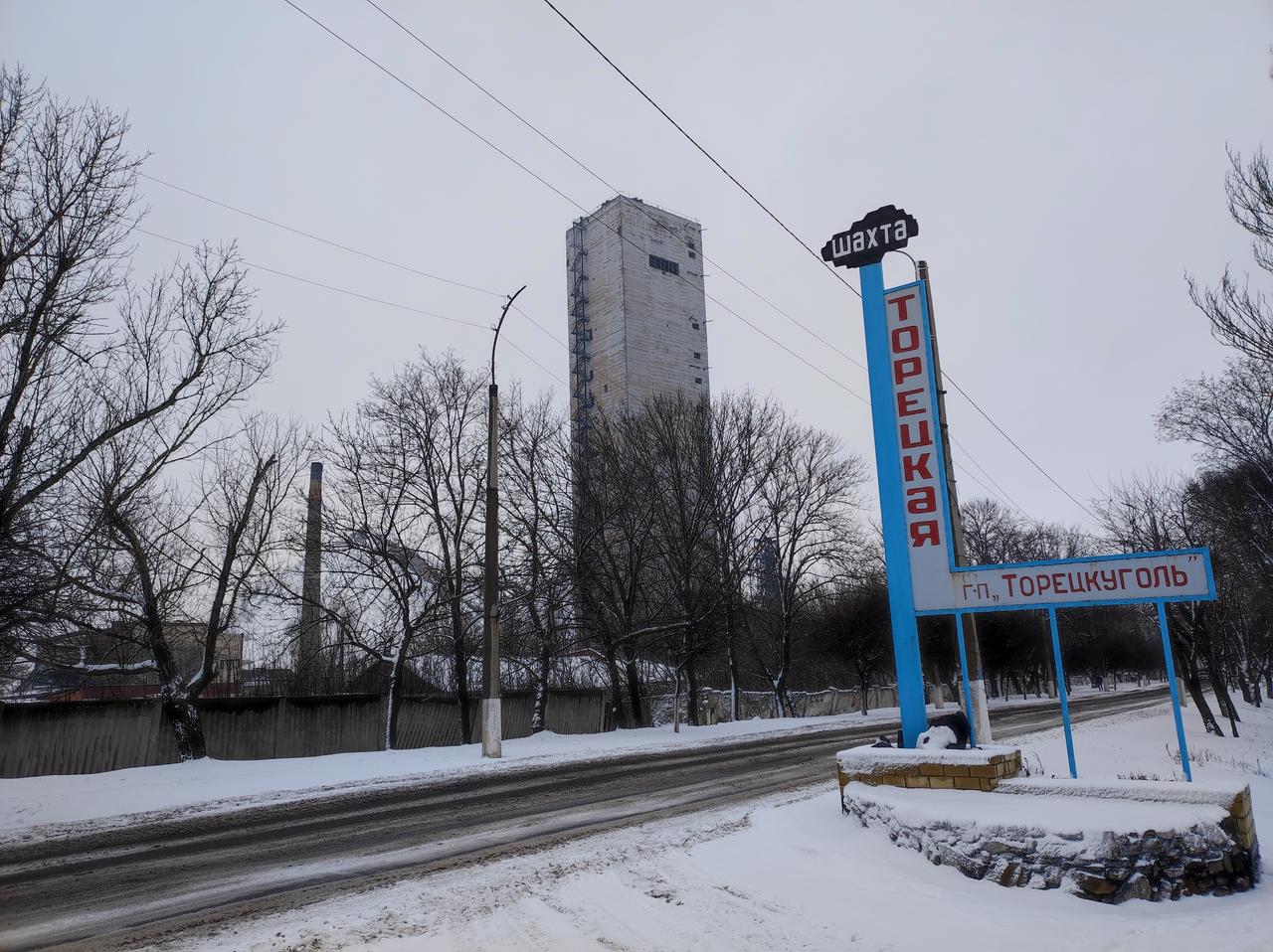 Eine schneeverscheite Straße, daneben ein Turm und ein Schild des Bergwerks Torezk Eine schneeverscheite Straße, daneben ein Turm und ein Schild des Bergwerks Torezk