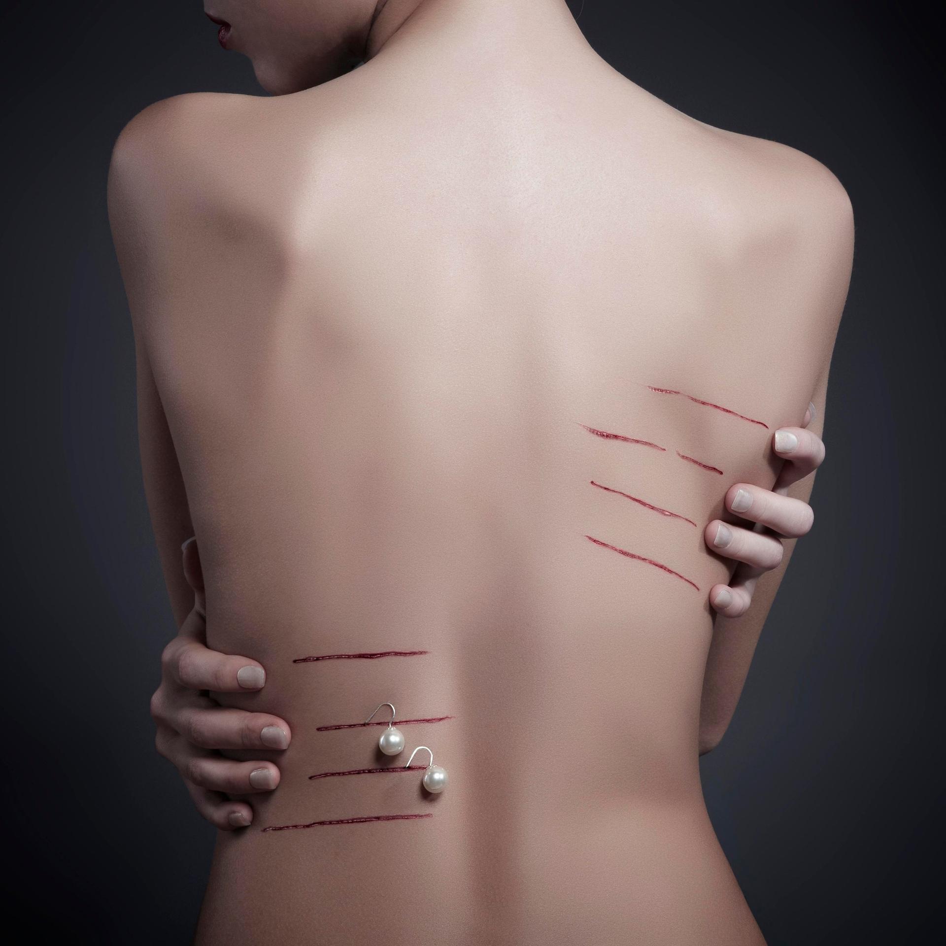 Rücken einer Frau, durch Fingernägel zerkratzt, Wunde mit Ohringen geschmückt