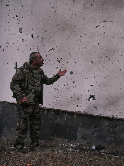 Ein Mann zeigt auf eine durch Grananten beschädigte Wand in der armenischen Stadt Jermuk am 15. September 2022