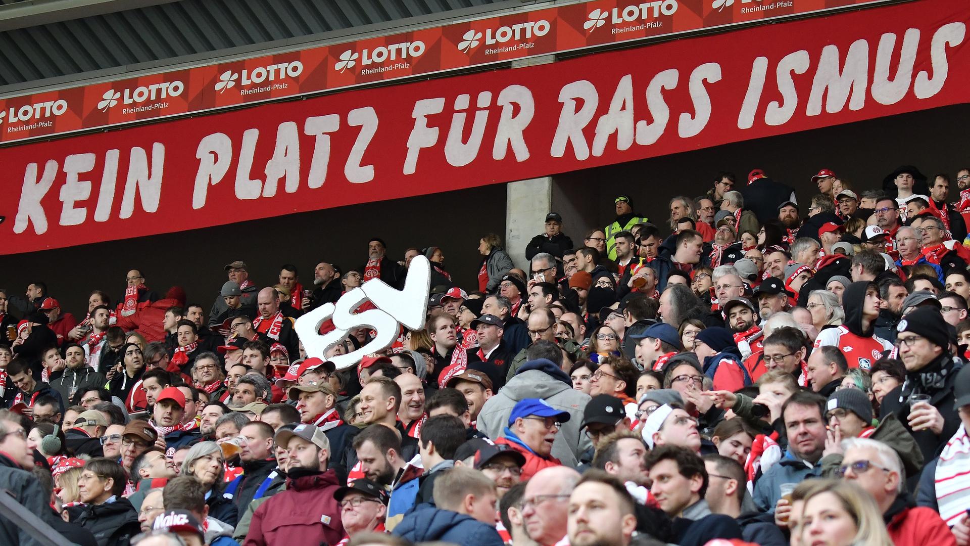 Das Foto zeigt Fußball-Fans und ein Schild mit den Worten "Kein Platz für Rassismus". Das Foto zeigt Fußball-Fans und ein Schild mit den Worten "Kein Platz für Rassismus".