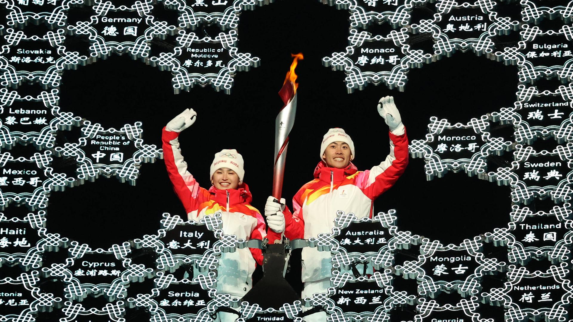 Die uigurische Langläuferin Dinigeer Yilamujian entzündet das Olympische Feuer bei den Winterspielen in Peking. Die uigurische Langläuferin Dinigeer Yilamujian entzündet das Olympische Feuer bei den Winterspielen in Peking.