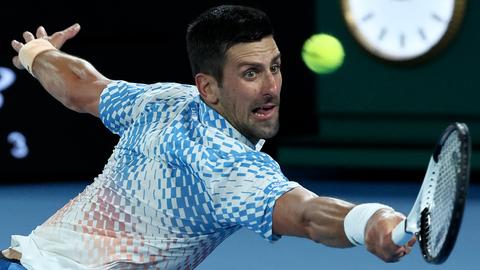 Auf dem Bild sieht man den serbischen Tennisspieler Novak Djokovic in Nahaufnahme. Er spielt einen Ball zurück und hat den Mund leicht geöffnet.