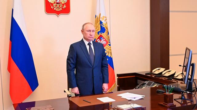 Der russische Präsident Wladimir Putin im Kreml am Schreibtisch. Hinter ihm steht eine russische Fahne.