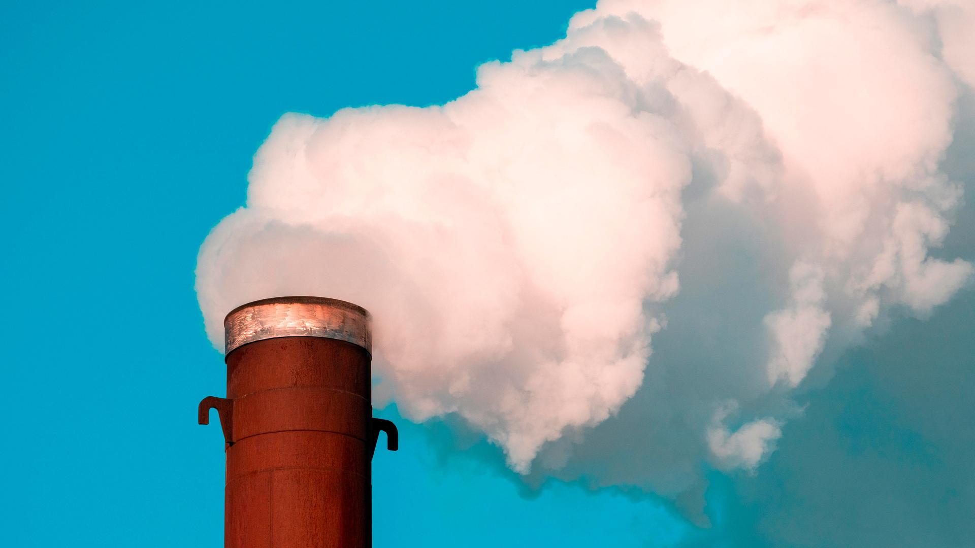 Verschmutzte Luft mit weißem Rauch strömt aus einem Industrieschornstein. Verschmutzte Luft mit weißem Rauch strömt aus einem Industrieschornstein.