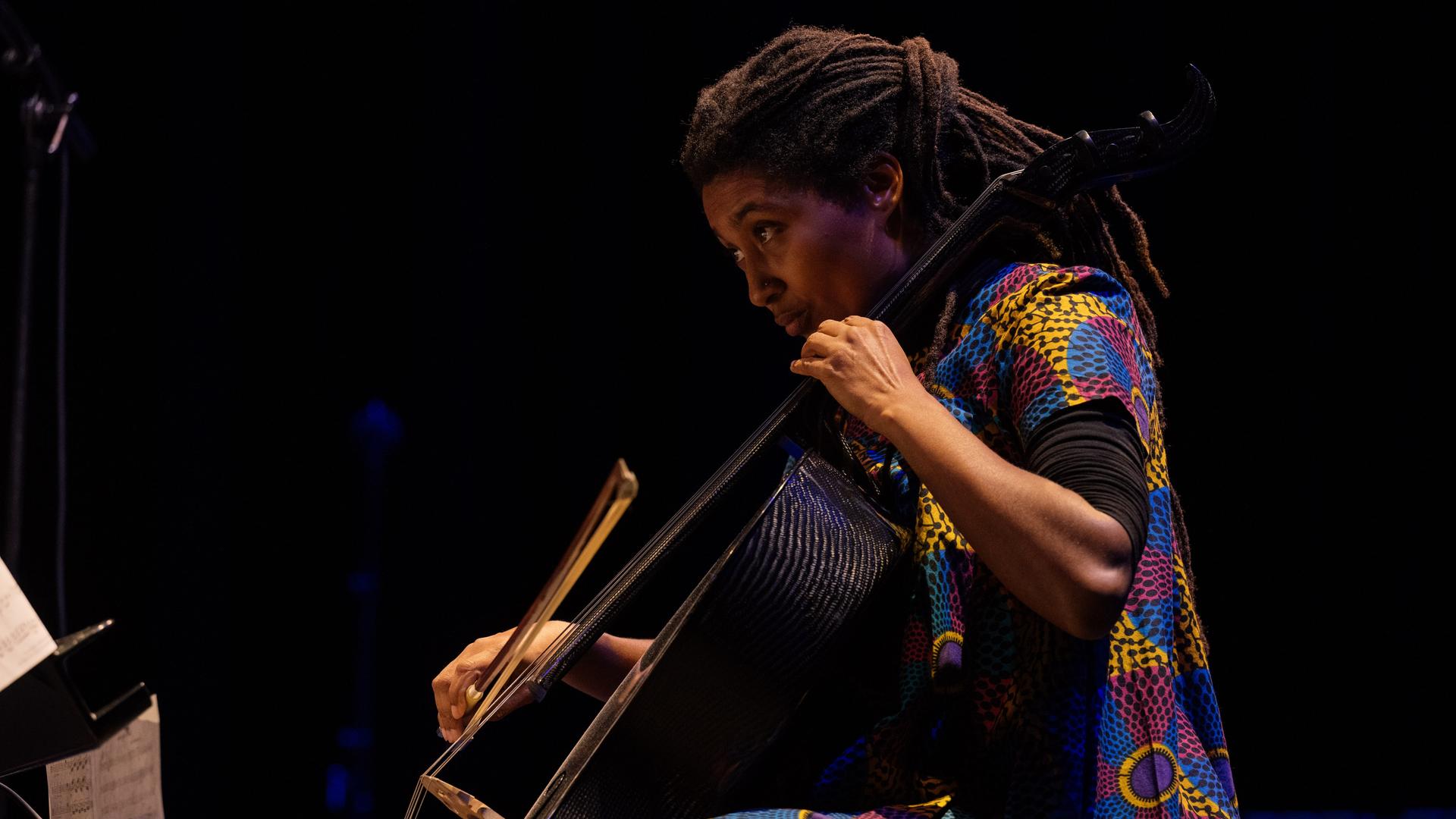 Auf dem Bild sehen wir die Cellistin Tomeka Reid im Profil an ihrem Cello. Auf dem Bild sehen wir die Cellistin Tomeka Reid im Profil an ihrem Cello.