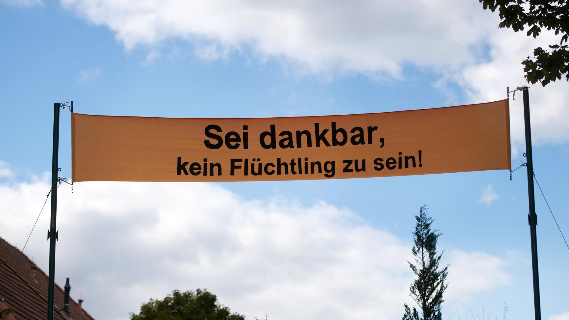 Ein gelbes Banner, auf dem "Sei dankbar, kein Flüchtling zu sein" steht