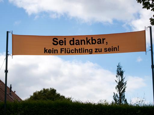 Ein gelbes Banner, auf dem "Sei dankbar, kein Flüchtling zu sein" steht
