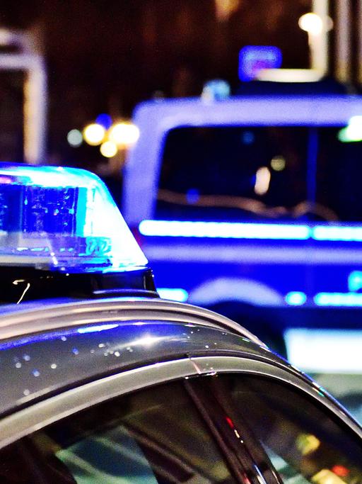 Zwei Polizeiwagen mit Blaulicht stehen nachts auf der Straße