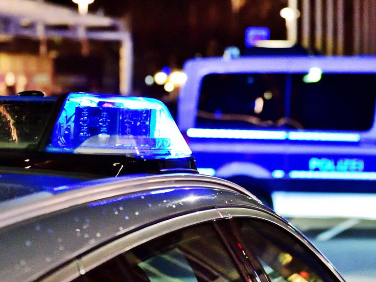 Zwei Polizeiwagen mit Blaulicht stehen nachts auf der Straße