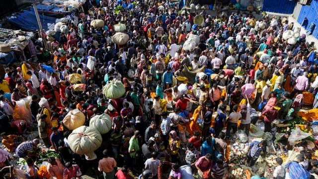 Indien, Kalkutta: Viele Menschen und Verkäufer stehen dicht nebeneinander auf einem Markt.